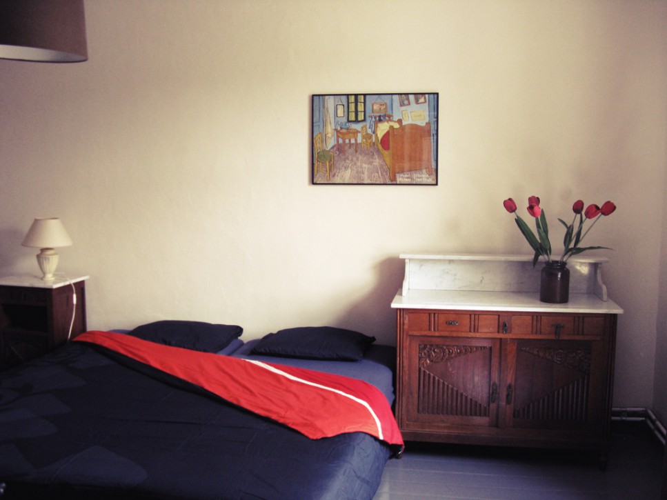 Spacious bedroom at the front of the house with large bed and sink.