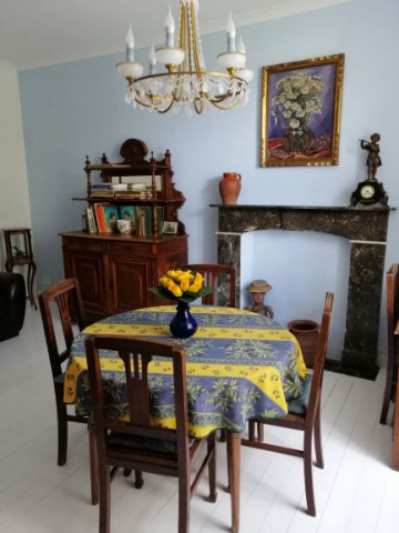 Across the entrance hall from the main living area, there is a secondary lounge featuring sofas, a desk and a round table underneath a large light fixture.